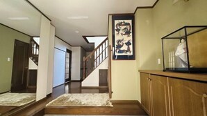 A hallway with a wooden floor, a glass cabinet, a framed artwork, and a staircase leading to another room. - Relaxing stay Fukunosou - Convenient Access Hakata (Fukuoka)