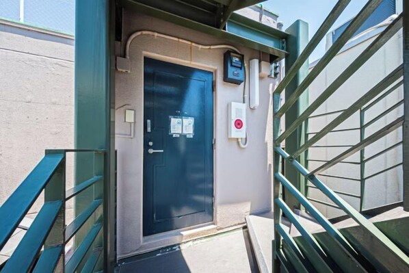 A door with a security keypad, a fire alarm, and a no-smoking sign. - Motomachi Hisui Building (Yokohama)