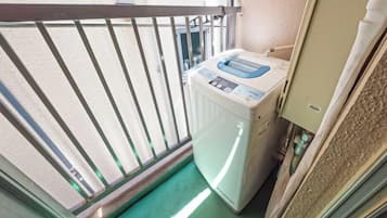 A compact room with a washing machine, a small window, and a door leading to another space.