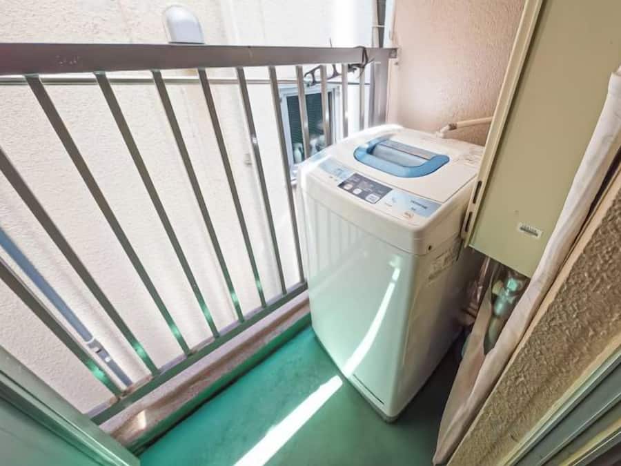 Habitación pequeña con lavadora, un ventanal y una puerta que da a otro espacio.
