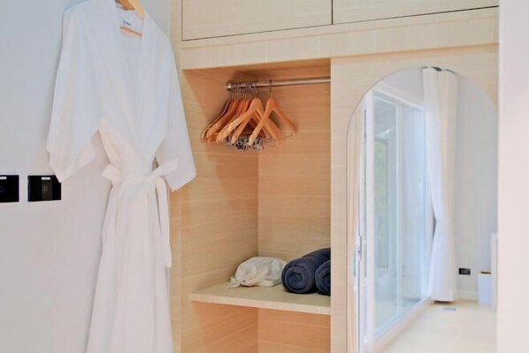 A hotel room with a wooden wardrobe, a hanging robe, and a glass shower enclosure. - The value of time pool villa Khaoyai (Pak Chong)