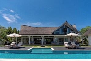 A two-story house with a swimming pool in front, covered outdoor seating, and a thatched roof. - Casa Del Mar (Bali)