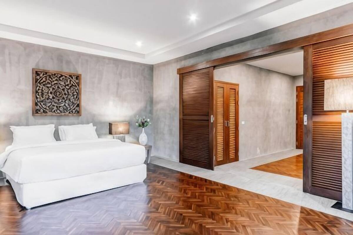 Une chambre à coucher avec un lit, une armoire en bois et un parquet à motifs en chevrons.