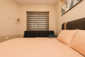 A bedroom with a bed, a window with blinds, a bedside table, and a wall-mounted lamp. - Batu Pahat Santalia Villa 4BR 12pax Private Pool (Simpang Kanan)
