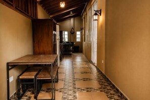 A hallway with a wooden table and bench, tiled flooring, and a kitchen area in the distance. - Batu Pahat Santalia Villa 4BR 12pax Private Pool (Simpang Kanan)