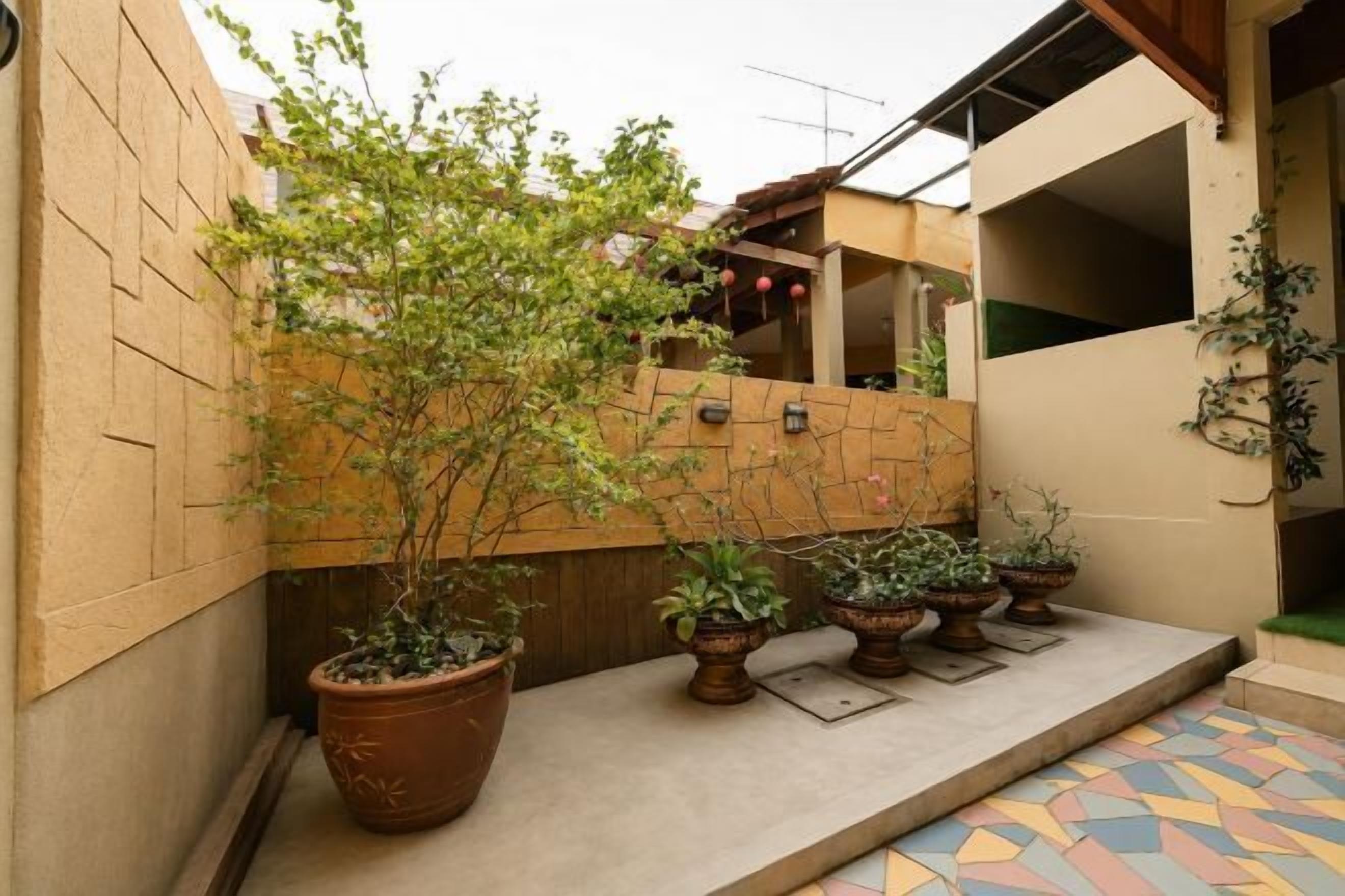 A courtyard with potted plants, a tiled floor, and a brick wall.