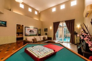 A pool table in a room with a sofa, a welcome sign, and a view of a pool. - Batu Pahat Santalia Villa 4BR 12pax Private Pool (Simpang Kanan)