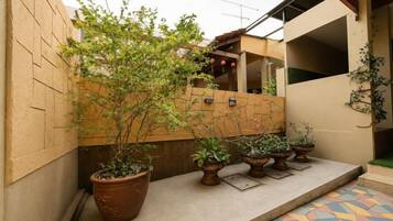 A courtyard with potted plants, a tiled floor, and a brick wall.