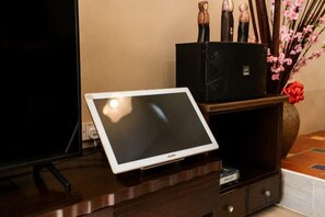 A tablet on a wooden desk with a black speaker and decorative items. - Batu Pahat Santalia Villa 4BR 12pax Private Pool (Simpang Kanan)