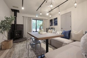A modern living room with a fireplace, a dining table, and a sofa. - [TV] Luxury adult secret base villa 120 ㎡ Sauna, stone bath, bonfire, BBQ [Zen Building] (Miyota)