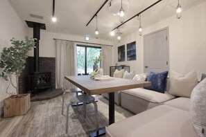 A modern living room with a fireplace, a dining table, and a sofa. - [TV] Luxury adult secret base villa 120 ㎡ Sauna, stone bath, bonfire, BBQ [Zen Building] (Miyota)