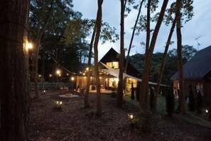 A rustic cabin with a porch, surrounded by trees and string lights. - [TV] Luxury adult secret base villa 120 ㎡ Sauna, stone bath, bonfire, BBQ [Zen Building] (Miyota)