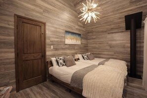 A bedroom with a wooden floor, a bed with pillows, a painting on the wall, and a ceiling light fixture. - [TV] Luxury adult secret base villa 120 ㎡ Sauna, stone bath, bonfire, BBQ [Zen Building] (Miyota)