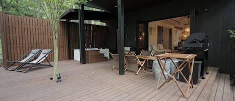 A wooden deck with outdoor furniture, a grill, and a bar area.