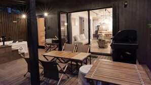 An outdoor wooden deck with a table and chairs, a grill, and a cozy seating area with cushions. - [TV] Luxury adult secret base villa 120 ㎡ Sauna, stone bath, bonfire, BBQ [Zen Building] (Miyota)
