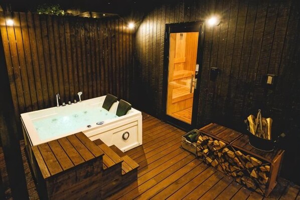 Un espace de bien-être avec un sol en bois, comprenant un jacuzzi, un sauna et un foyer.