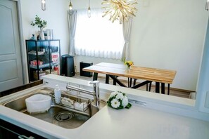 Una cocina moderna con un lavamanos, encimera y una mesa de comedor con sillas.