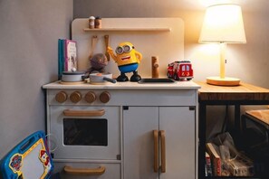 Un coin cuisine avec une cuisinière, un jouet à l’effigie d’un personnage de dessin animé et une lampe.