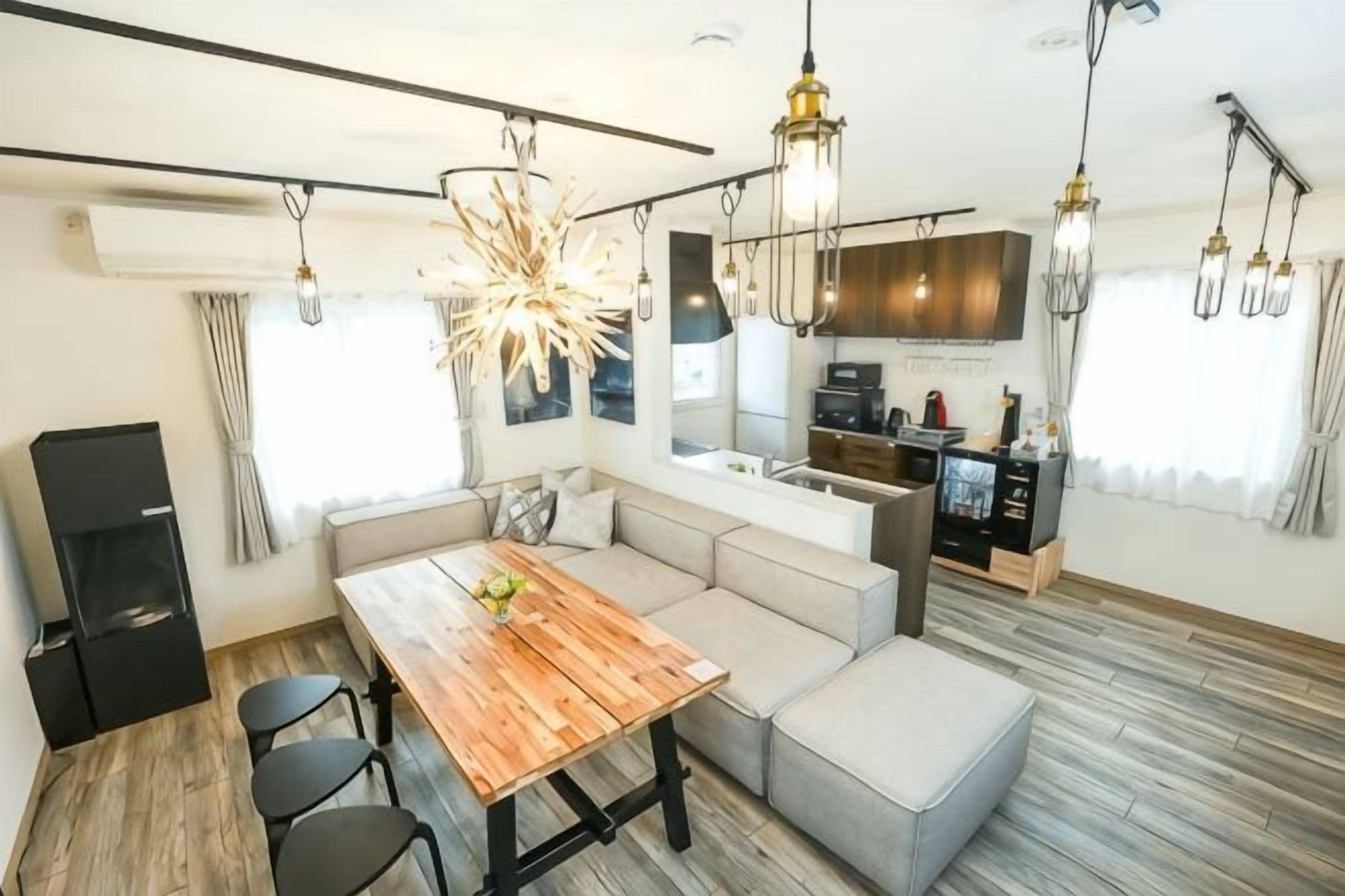 Une cuisine moderne dotée d’un four et d’un micro-ondes encastr és, un coin repas avec une table et des chaises en bois, et une grande fenêtre avec des rideaux.