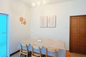 Ein Essbereich mit Tisch, Stühlen, einer Wandleuchte und einer Tür.