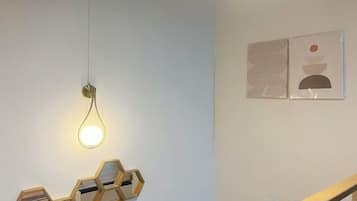 A room with a hanging light fixture, hexagonal wall decor, and two framed artworks.
