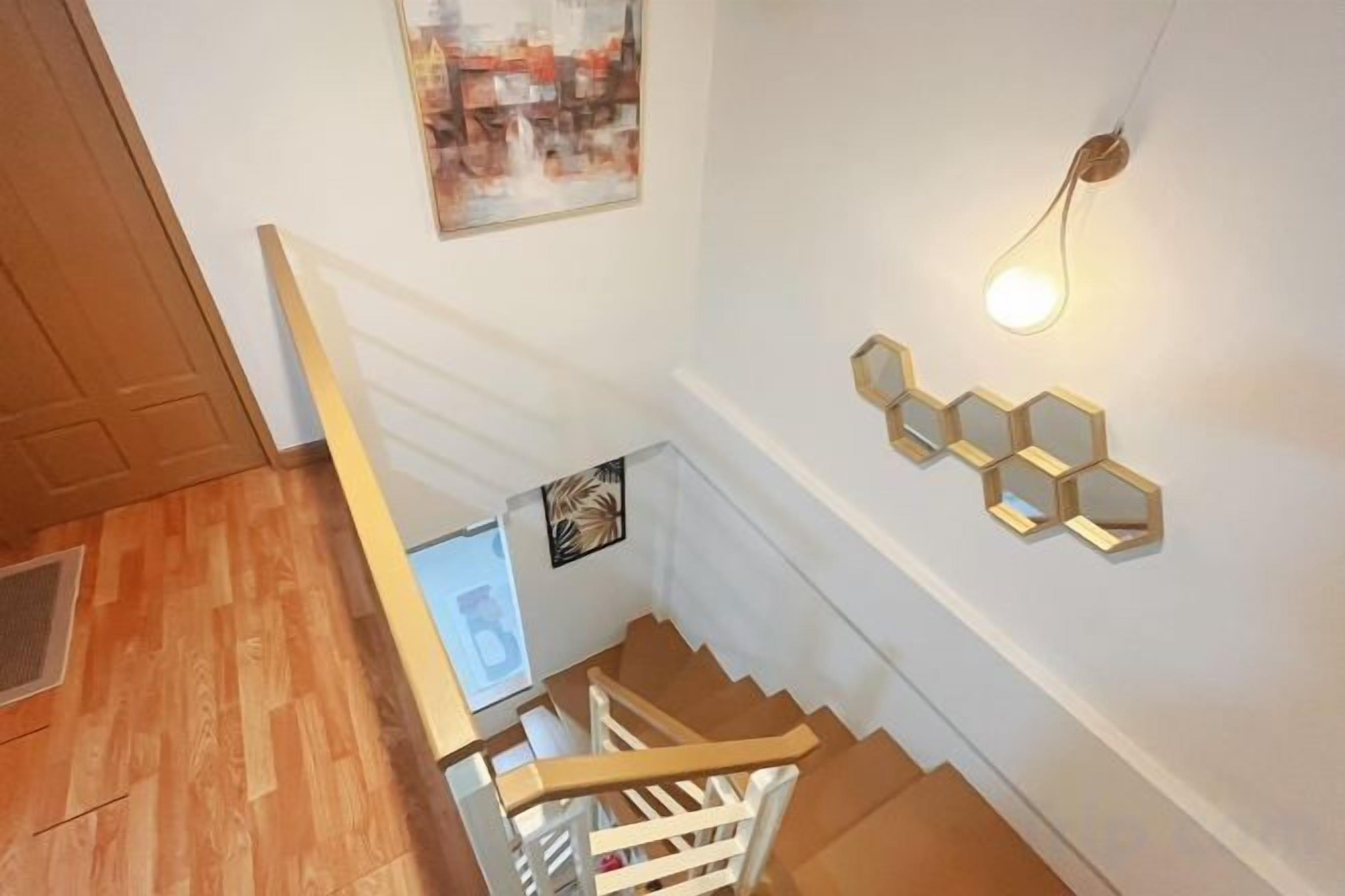 A staircase with a wooden handrail and a wall-mounted light fixture.
