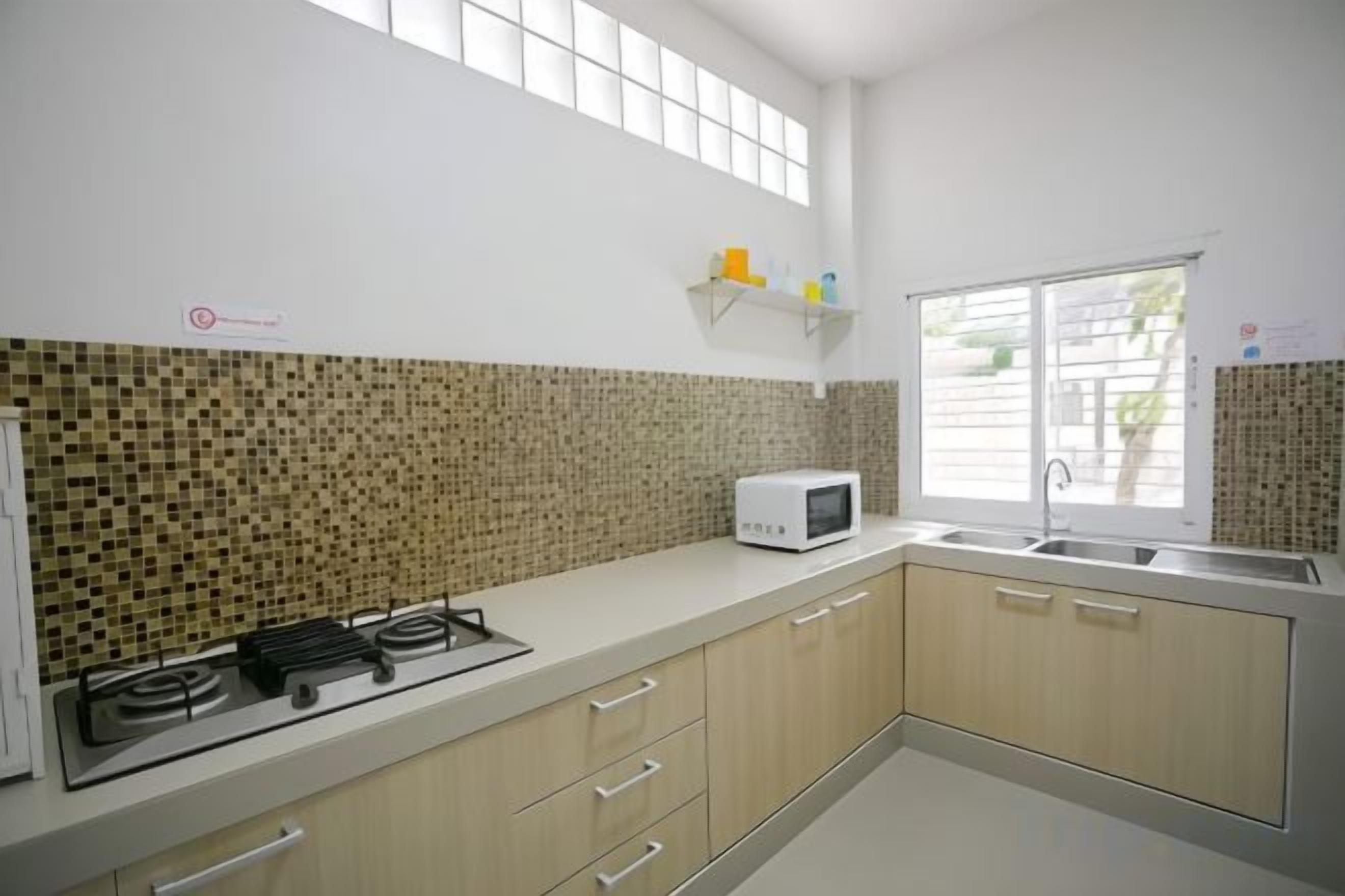A kitchen with a gas stove, microwave, and a window.