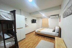 A bedroom with bunk beds, a single bed, a flat-screen TV, a window with curtains, and a wall-mounted air conditioner. - DeliZia de Villa Homestay Satun (Satun)