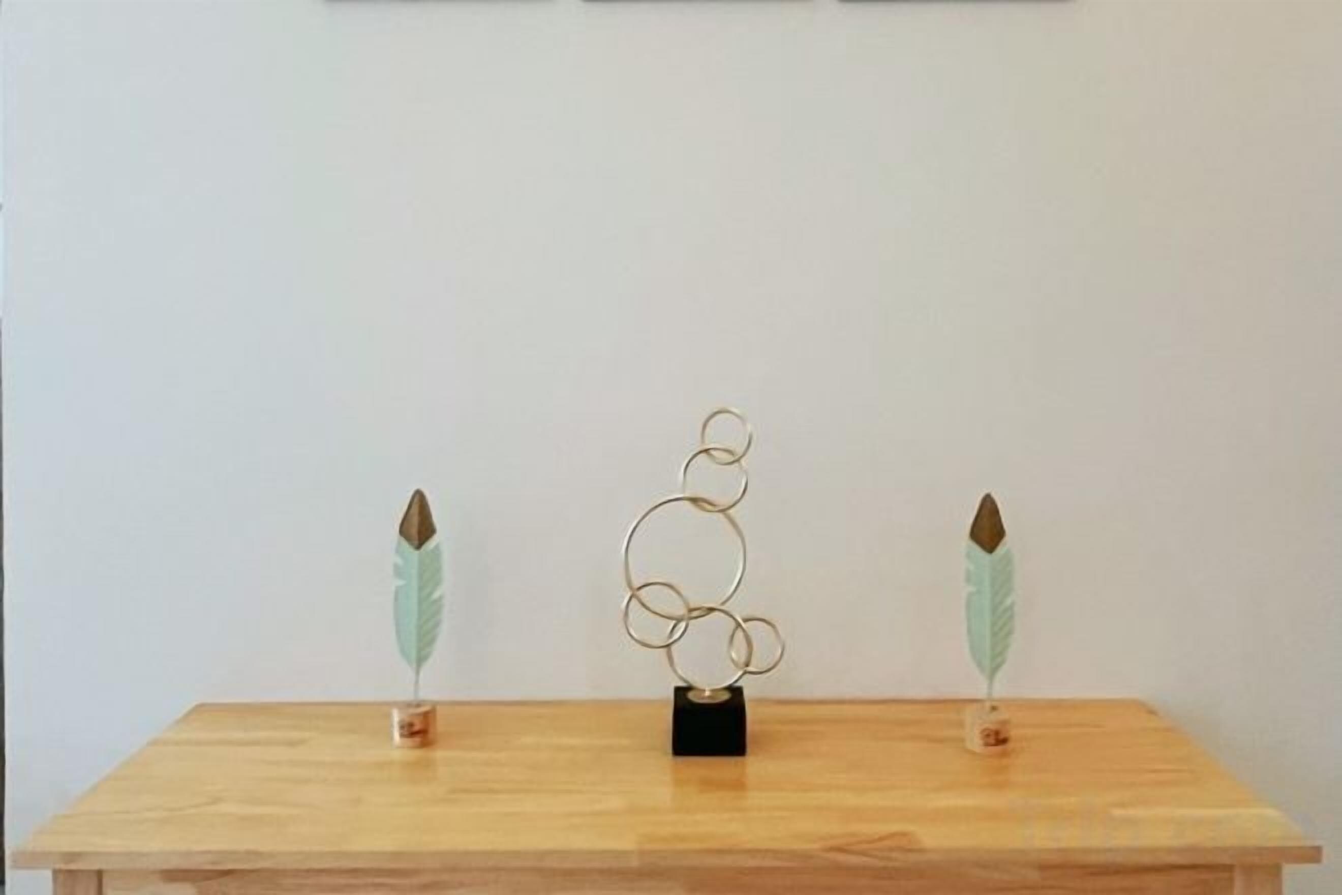 A wooden table with a metal sculpture in the center.