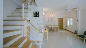A spacious living area with a staircase, a dining table, and a ceiling fan. - DeliZia de Villa Homestay Satun (Satun)
