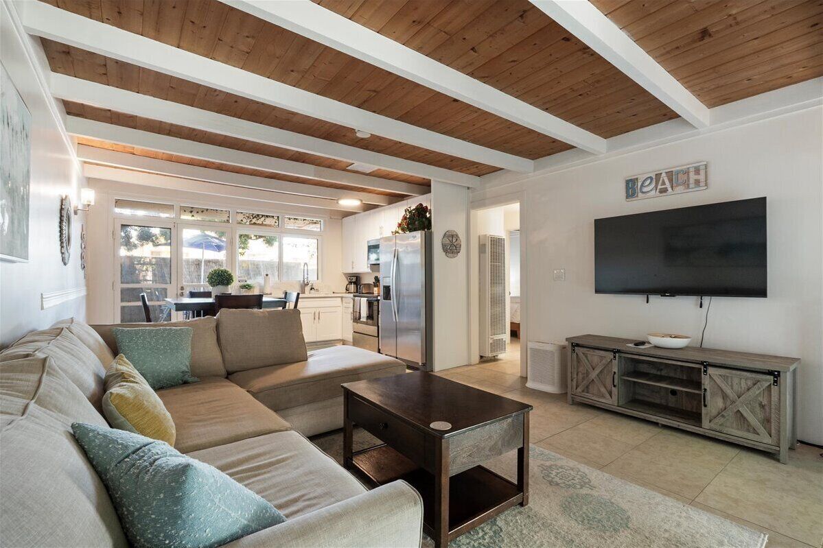 A modern living room with a sectional sofa, a coffee table, and a TV mounted on the wall.
