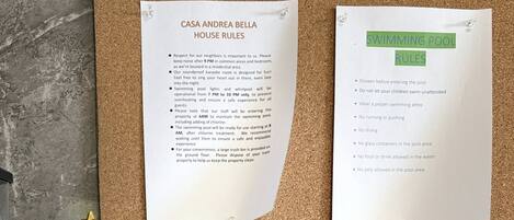 A corkboard with two notices: 'Casa Andrea Bella House Rules' and 'Swimming Pool Rules'.