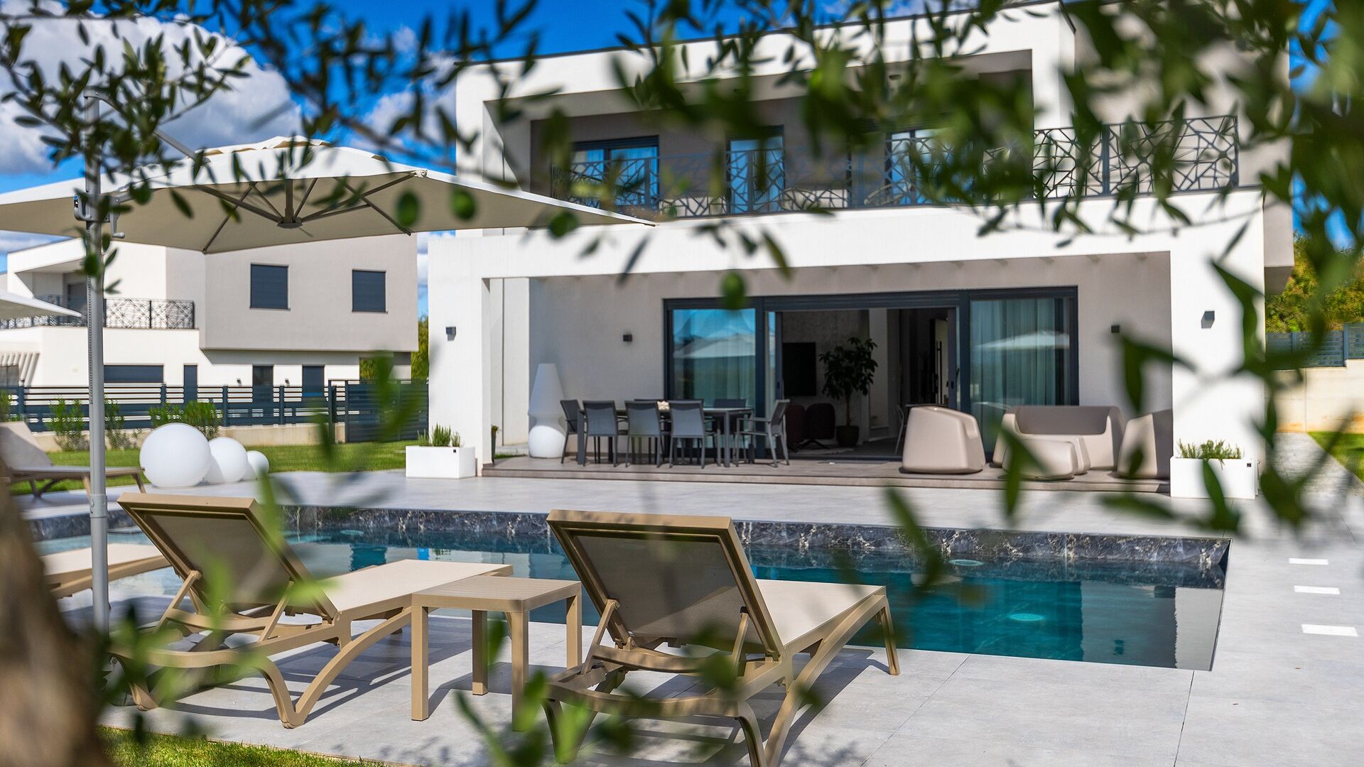 Une maison moderne dotée d’une piscine, de mobilier d’extérieur et d’un espace patio.