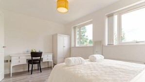 Een slaapkamer met een bed, een bureau, een stoel, een kledingkast en een raam.