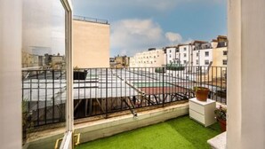 A balcony with a view of a cityscape, a small grassy area, and a white cabinet. - South Kensington - Cromwell Rd Residence (London)