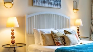 A hotel room with a white bed, multiple pillows, a blue blanket, and two wall-mounted lamps. - South Kensington - Cromwell Rd Residence (London)