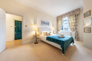 A bedroom with a bed, bedside lamps, a window with curtains, and a door leading to another room. - South Kensington - Cromwell Rd Residence (London)