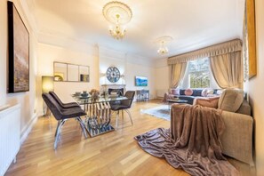 A spacious living room with a dining area, a sofa set, and a television. - South Kensington - Cromwell Rd Residence (London)