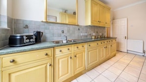 A kitchen with yellow cabinets, a large mirror, a sink, and a toaster on the counter. - South Kensington - Cromwell Rd Residence (London)