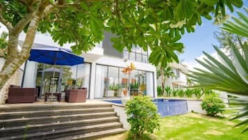 A modern house with a pool, outdoor seating, and a staircase leading to the entrance.