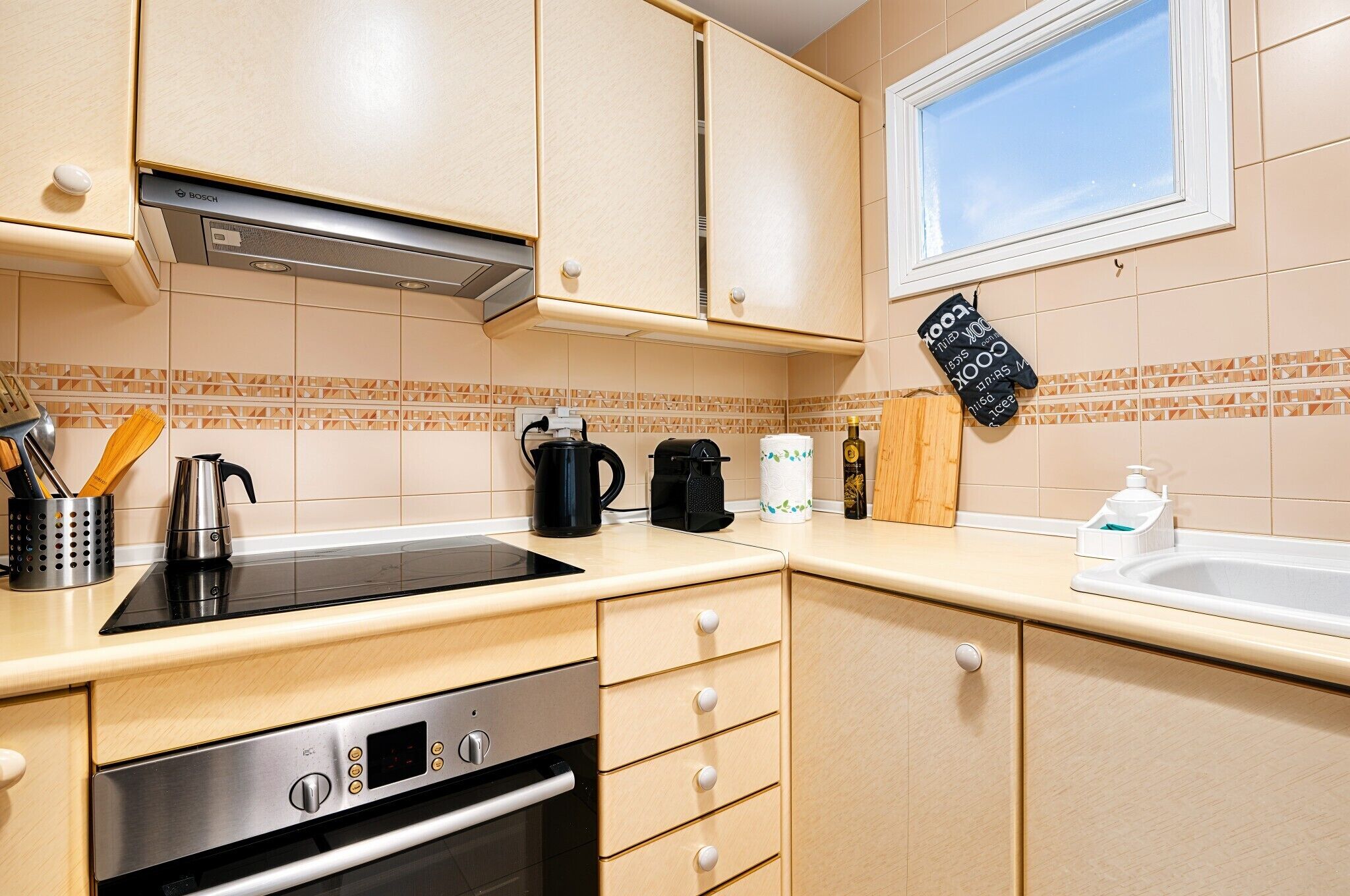 A kitchen with a Bosch oven, a coffee maker, and a kettle on the counter.