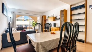 A dining area with a table, chairs, a sofa, and a balcony view.