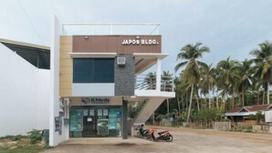 A modern building with a sign reading "JAPOS BLDC." and a pharmacy named "KMedis Pharmacy" on the ground floor. - RedDoorz @ Happy Stay Apartelle (Dauis)