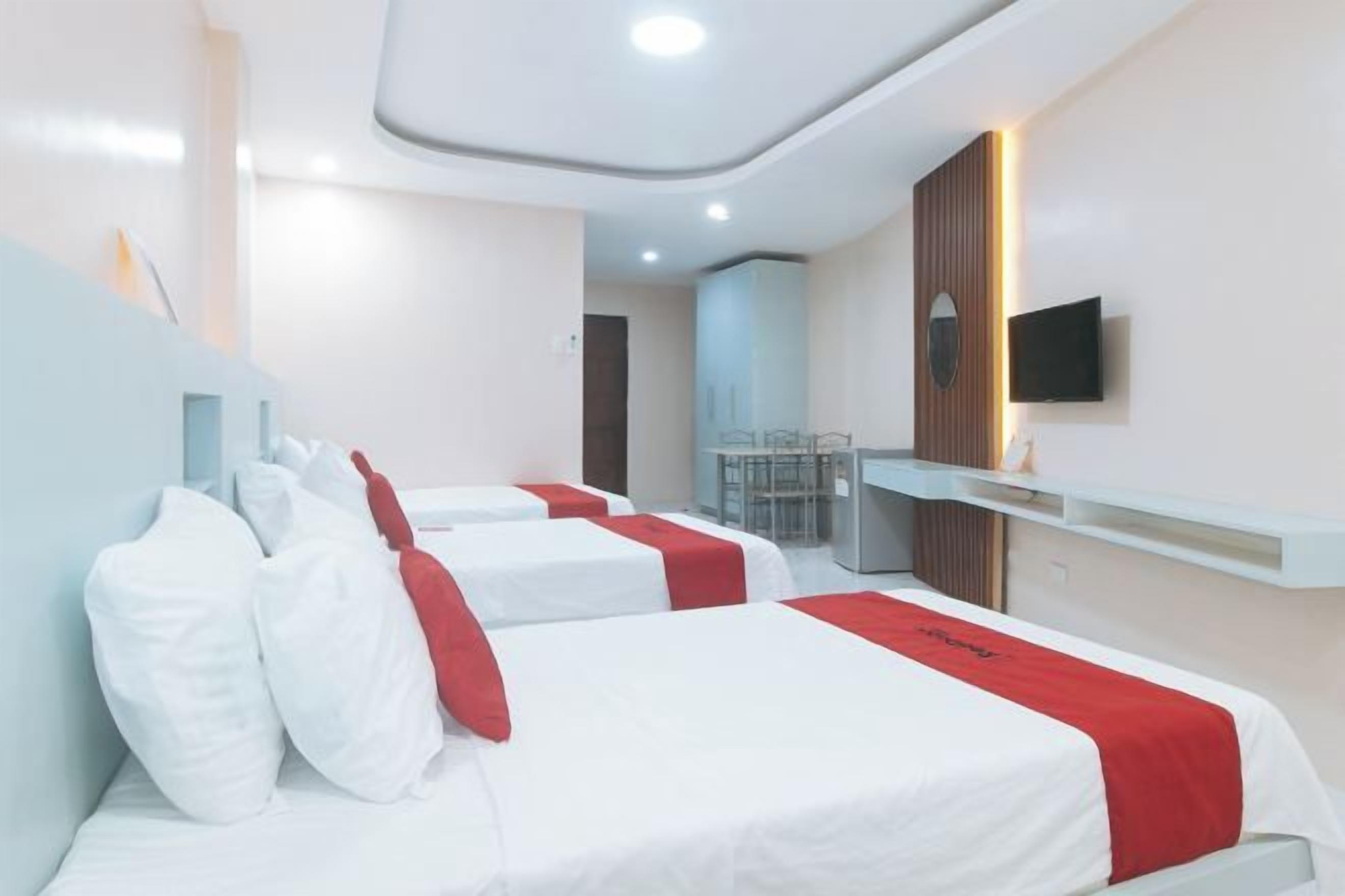 Una habitación de hotel con dos camas, un televisor montado en la pared y una mesita.