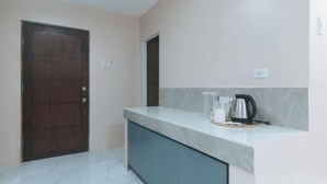 A kitchen with a marble countertop, a coffee maker, and a kettle. - RedDoorz @ Happy Stay Apartelle (Dauis)