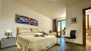 A hotel room with a large bed, a chair, a desk, and a painting on the wall. - Beautiful private villa for 10 people with A/C, WIFI, pool, TV and panoramic view (Scopello)