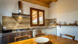 A kitchen with a wooden table, a stove, and a window with a view. - Beautiful private villa for 10 people with A/C, WIFI, pool, TV and panoramic view (Scopello)