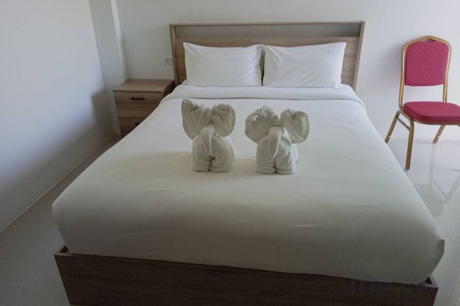 Una cama con sábanas blancas y dos toallas con forma de elefantes.