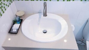Une salle de bain avec un lavabo blanc, une douchette et des toilettes.
