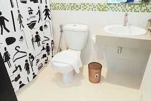 Een badkamer met toilet, wastafel en een muur met zwart-wit iconen.